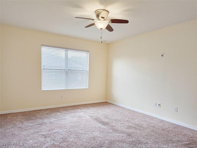 carpeted spare room with baseboards and ceiling fan