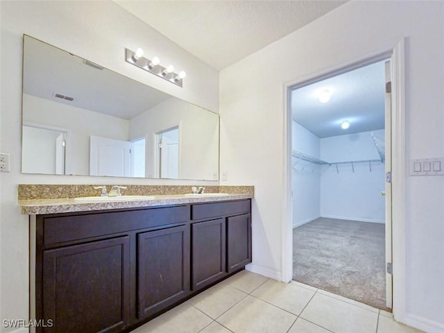 bathroom featuring a sink, a spacious closet, double vanity, and tile patterned flooring