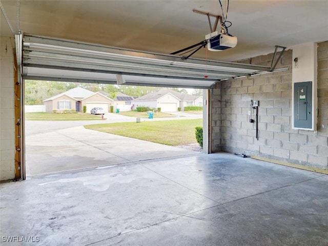 garage featuring concrete block wall, electric panel, and a garage door opener