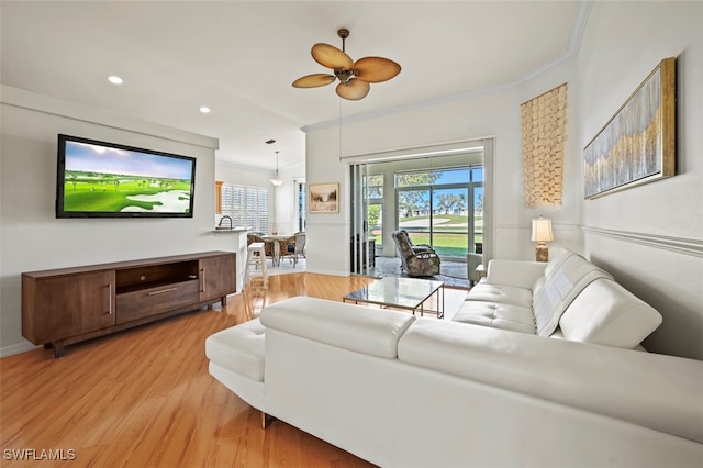 living room with a wealth of natural light, light wood-style floors, ornamental molding, and recessed lighting