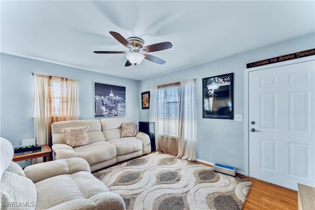 living area featuring baseboards, wood finished floors, and a ceiling fan