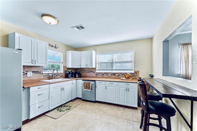 kitchen with visible vents, a sink, backsplash, stainless steel appliances, and light tile patterned floors