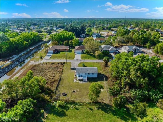 birds eye view of property featuring a forest view and a water view