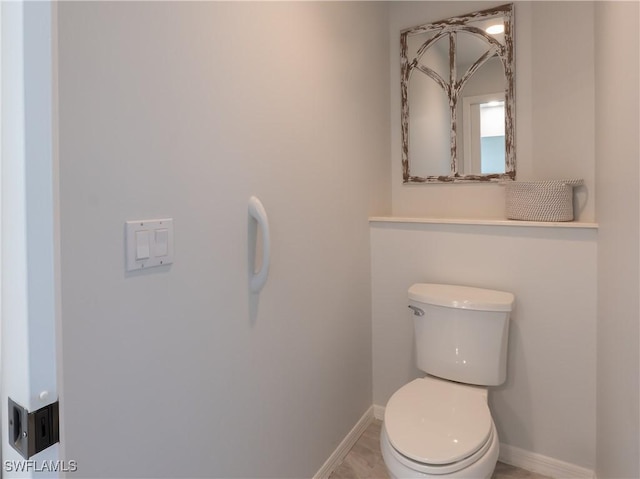 half bath featuring toilet and baseboards