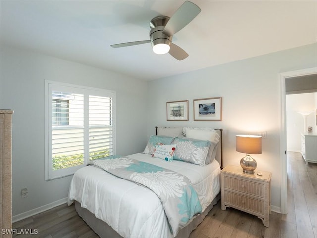 bedroom featuring baseboards, wood finished floors, and a ceiling fan