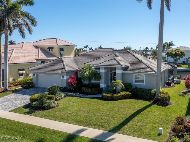 view of front of property with a front yard, a tiled roof, an attached garage, and stucco siding