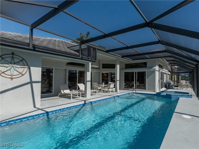 view of swimming pool with a patio area, glass enclosure, and a pool with connected hot tub