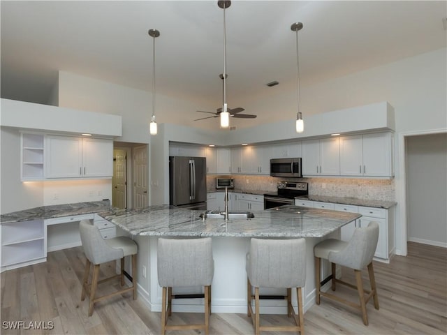 kitchen with open shelves, a sink, backsplash, stainless steel appliances, and a large island with sink