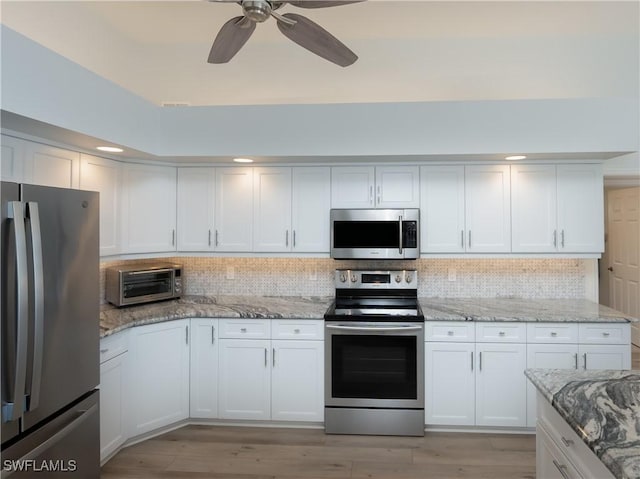 kitchen with stainless steel appliances, white cabinets, decorative backsplash, and a toaster