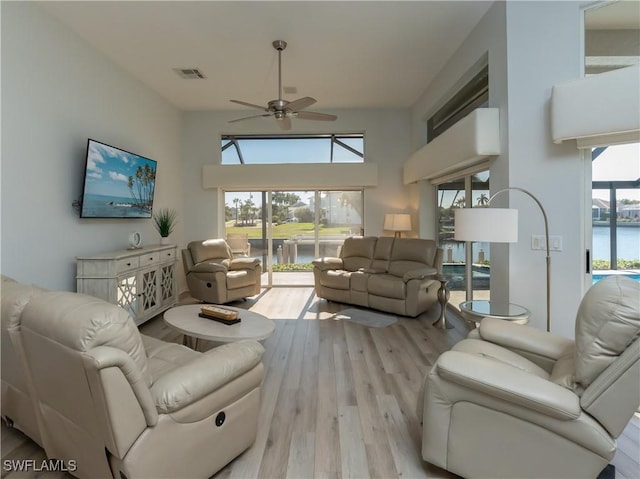 living room with a wealth of natural light, visible vents, a ceiling fan, and wood finished floors