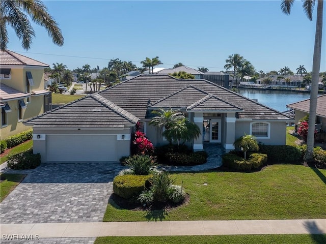 view of front facade with a front lawn, a tiled roof, stucco siding, driveway, and an attached garage