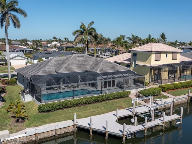 dock area featuring glass enclosure, a lawn, a water view, and boat lift