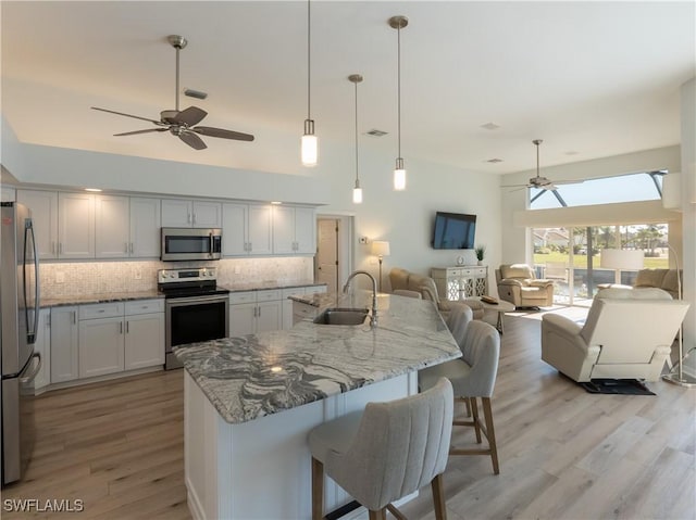 kitchen featuring open floor plan, appliances with stainless steel finishes, a ceiling fan, and a sink