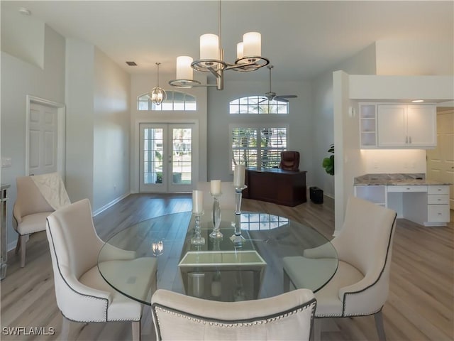 dining area featuring light wood finished floors, french doors, and an inviting chandelier