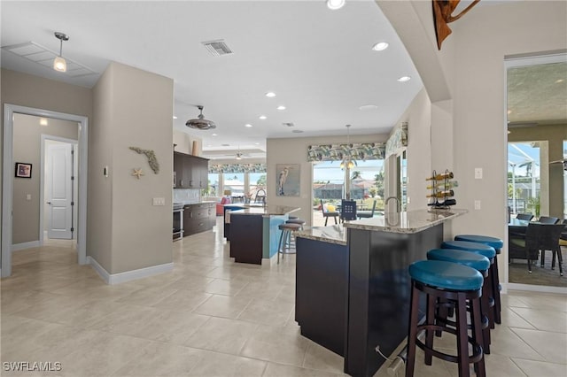 kitchen featuring visible vents, light tile patterned flooring, recessed lighting, a kitchen island with sink, and a kitchen breakfast bar