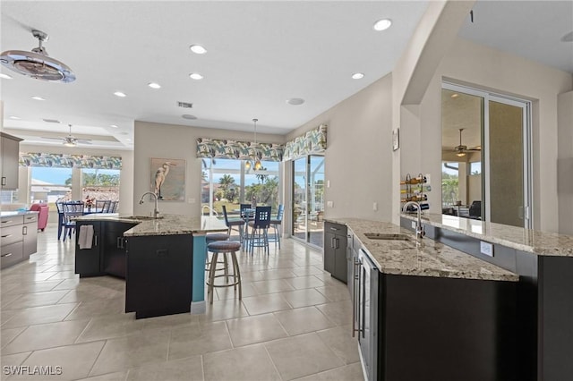 kitchen featuring a sink, visible vents, a large island with sink, and a ceiling fan