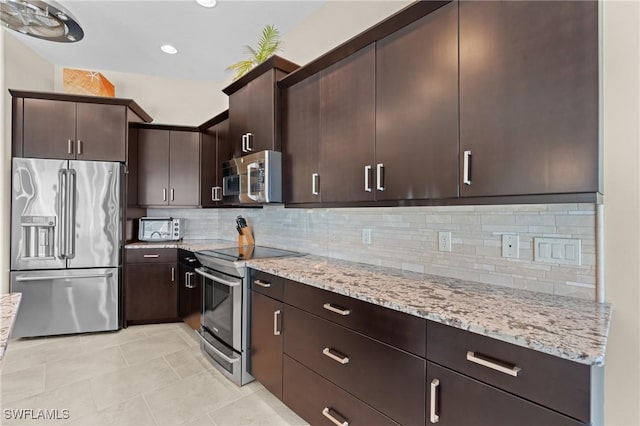 kitchen with backsplash, dark brown cabinetry, appliances with stainless steel finishes, light tile patterned floors, and light stone countertops