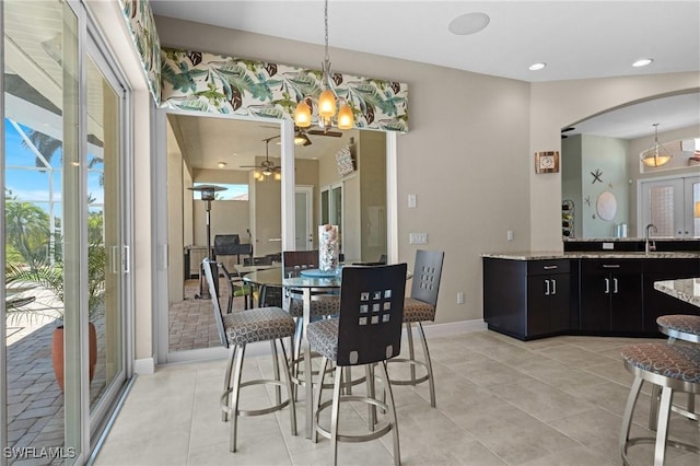 dining area featuring ceiling fan with notable chandelier, recessed lighting, arched walkways, light tile patterned floors, and baseboards