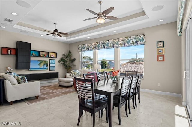 dining area featuring a tray ceiling, a ceiling fan, baseboards, and visible vents