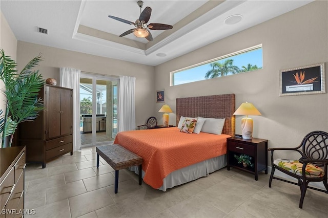 bedroom featuring light tile patterned floors, visible vents, a tray ceiling, ceiling fan, and access to exterior