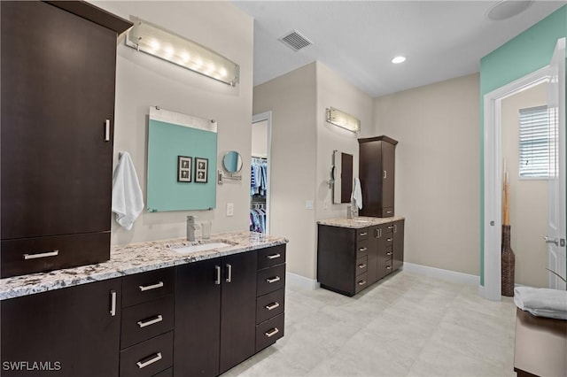 full bath with visible vents, two vanities, a sink, recessed lighting, and baseboards