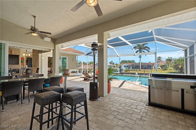 view of patio with a lanai, outdoor dining area, an outdoor pool, and ceiling fan