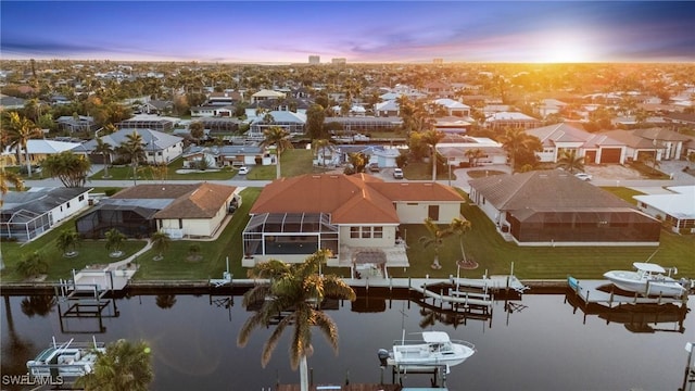 aerial view at dusk with a residential view and a water view