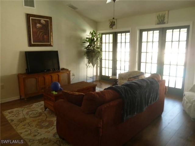 living room with visible vents, baseboards, and wood finished floors