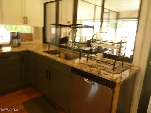 kitchen featuring a wealth of natural light, light stone countertops, and dishwasher