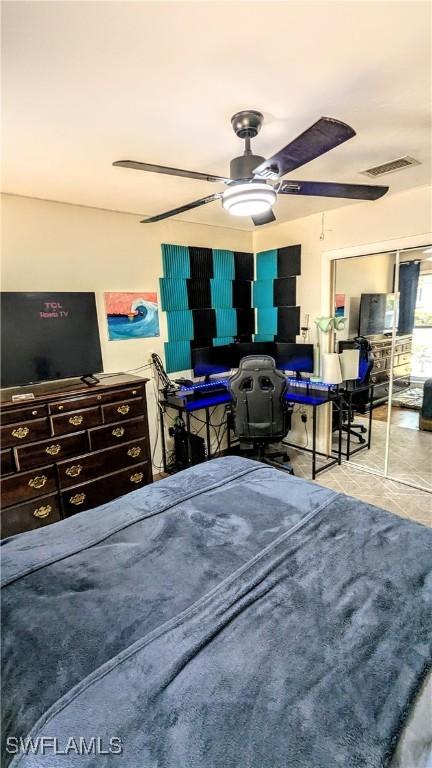 bedroom featuring tile patterned floors, visible vents, ceiling fan, and a closet