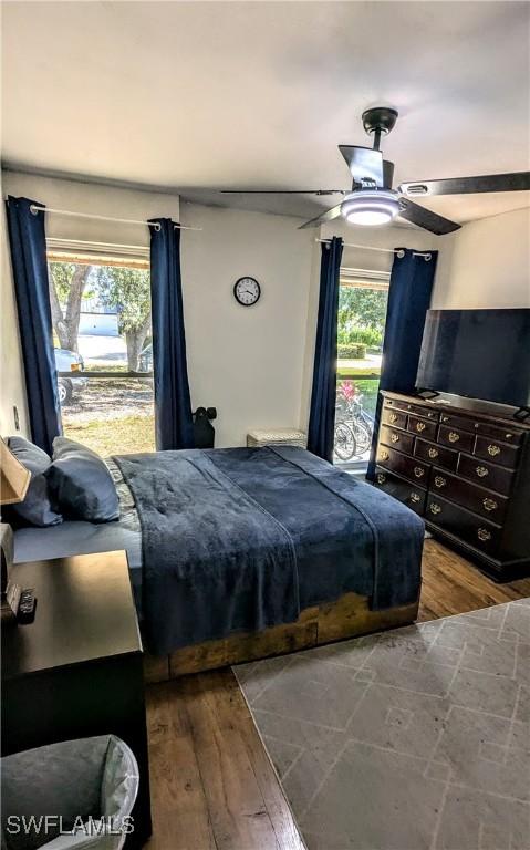bedroom featuring a ceiling fan, hardwood / wood-style floors, and multiple windows