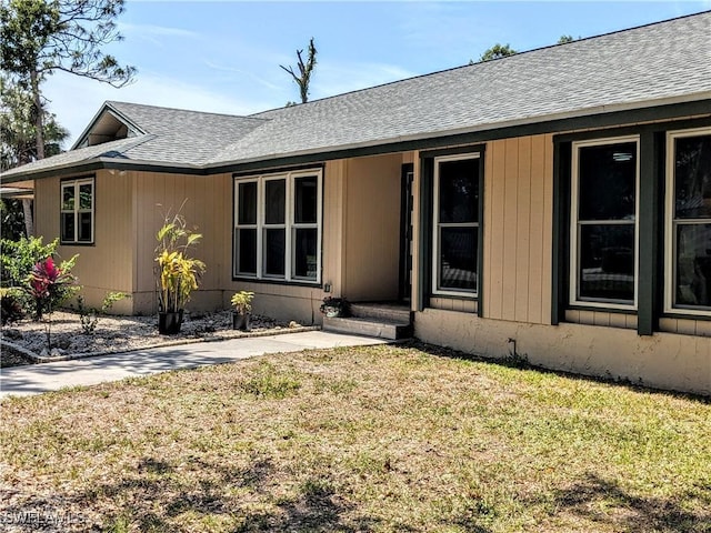 rear view of house with a yard and roof with shingles