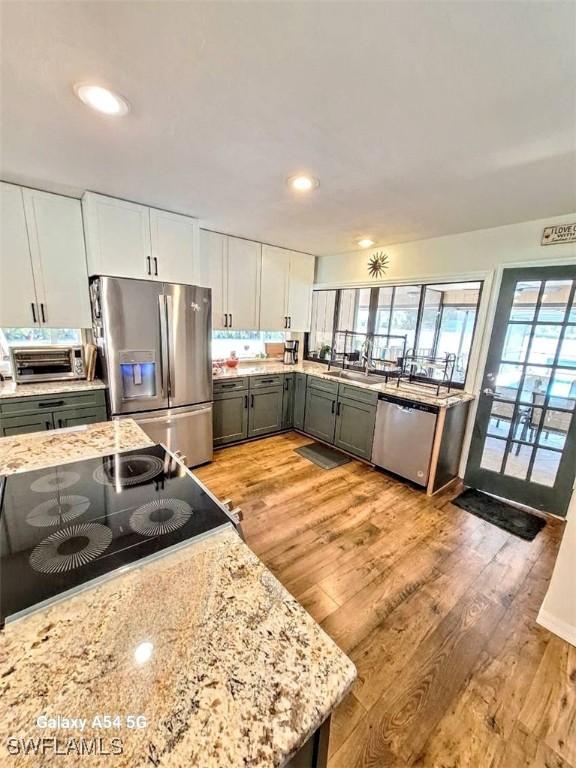 kitchen featuring light wood-type flooring, appliances with stainless steel finishes, a toaster, and recessed lighting