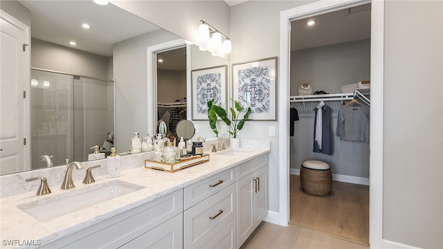 full bathroom with double vanity, recessed lighting, a stall shower, and a sink