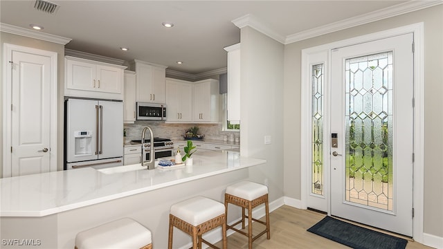 kitchen with premium appliances, a breakfast bar, crown molding, and visible vents