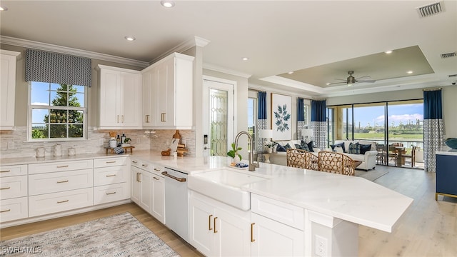 kitchen featuring visible vents, a sink, a tray ceiling, open floor plan, and dishwasher