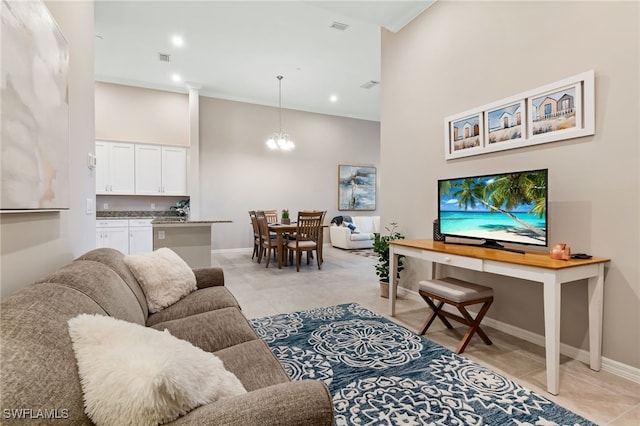 living area featuring light tile patterned floors, visible vents, a towering ceiling, and a chandelier