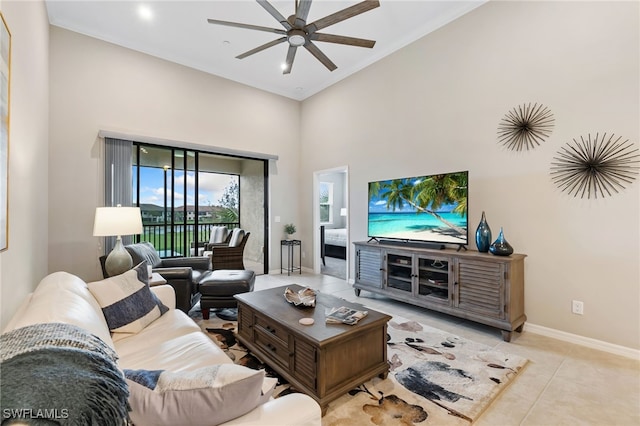 tiled living room featuring a ceiling fan, baseboards, and a towering ceiling