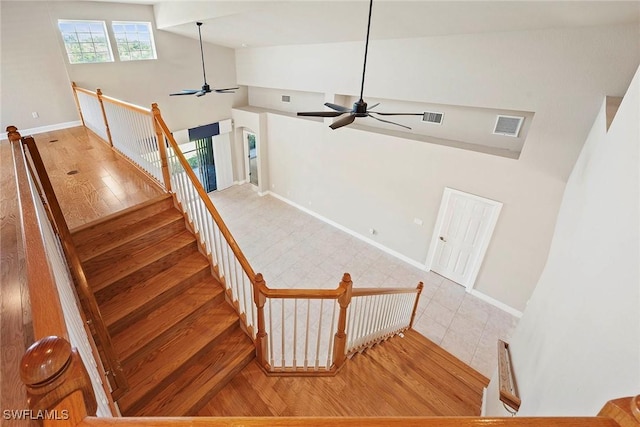 stairs with visible vents, high vaulted ceiling, a ceiling fan, and hardwood / wood-style flooring