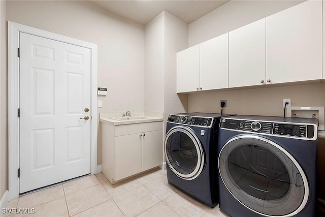 laundry room featuring washing machine and clothes dryer, light tile patterned floors, cabinet space, and a sink