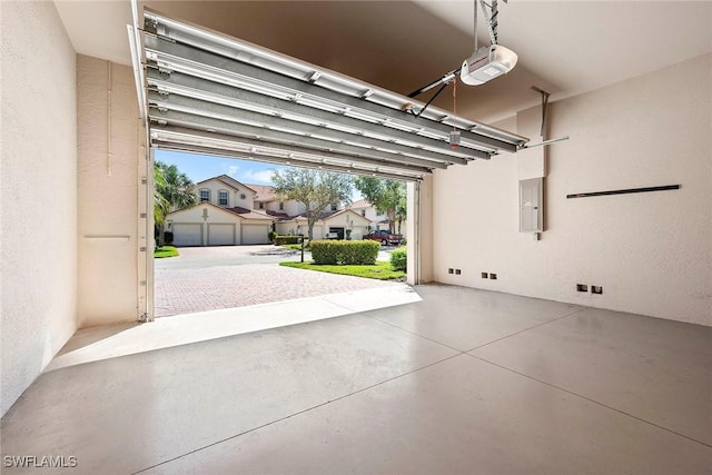 garage featuring electric panel, a garage door opener, a residential view, and a textured wall