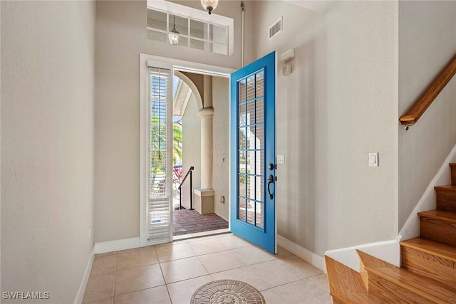 foyer entrance featuring visible vents, stairway, arched walkways, light tile patterned flooring, and baseboards