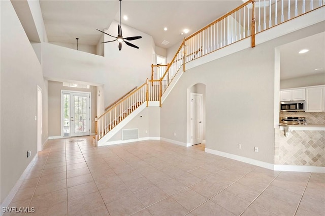 unfurnished living room with baseboards, stairway, french doors, light tile patterned flooring, and a ceiling fan