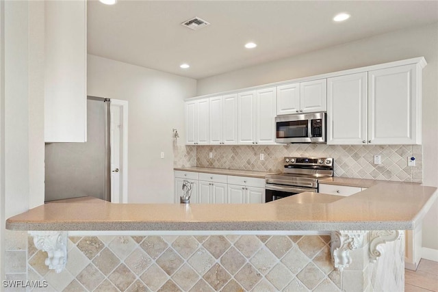 kitchen featuring decorative backsplash, light countertops, white cabinetry, and stainless steel appliances