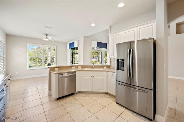 kitchen with white cabinetry, a peninsula, appliances with stainless steel finishes, and a sink