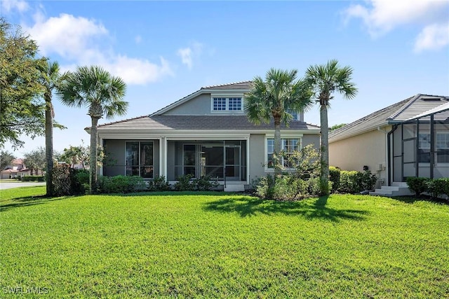 view of front of home with stucco siding, a front yard, and a sunroom