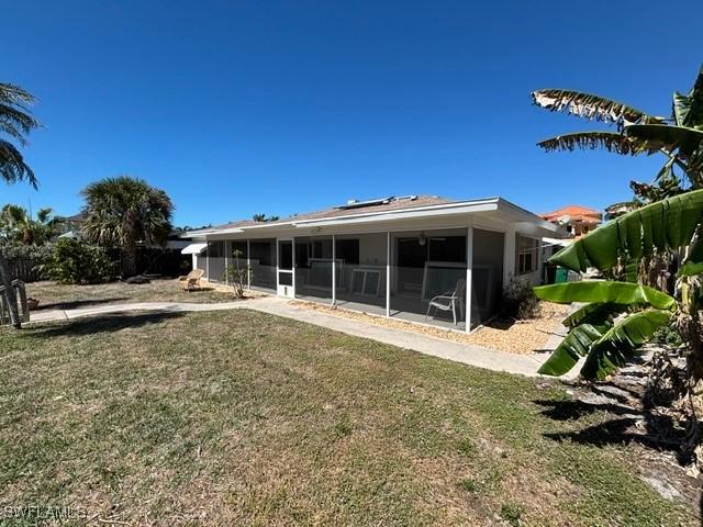 back of property featuring a lawn and a sunroom