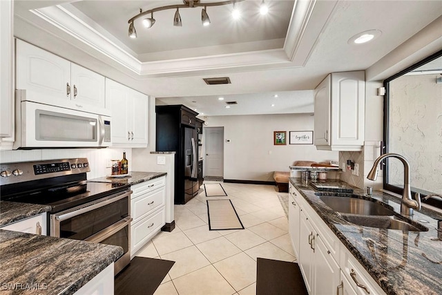 kitchen featuring white microwave, double oven range, a tray ceiling, ornamental molding, and a sink