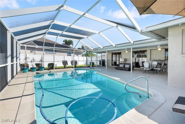 view of swimming pool with glass enclosure, a patio, a ceiling fan, fence, and a fenced in pool