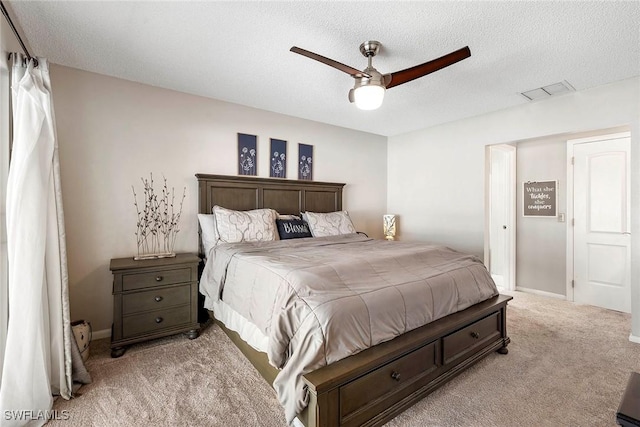 bedroom featuring visible vents, light carpet, a textured ceiling, and baseboards